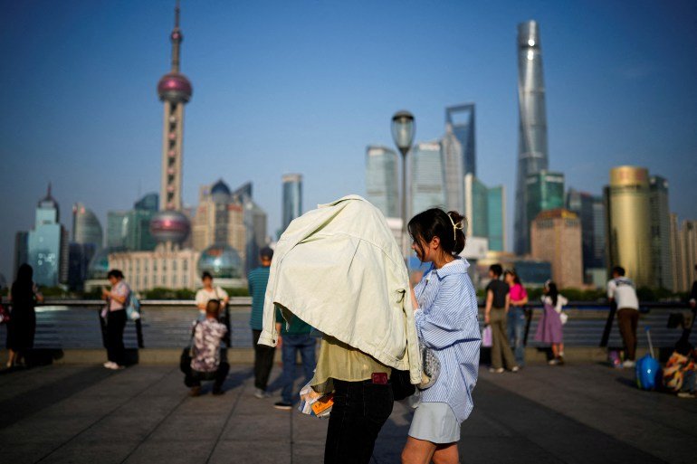 FILE PHOTO: A person uses clothing to protect themselves from the sun, as they walk on the Bund on a hot day, in Shanghai, China May 15, 2023. REUTERS/Aly Song/File Photo