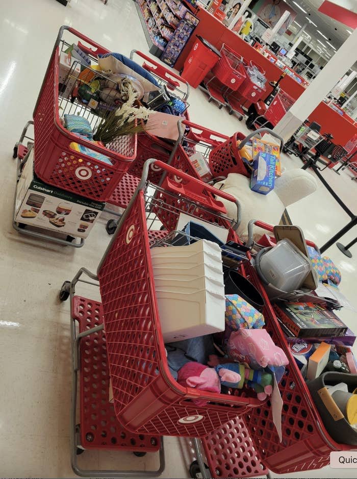 Shopping carts filled with various items, including toys and home goods, sitting in a retail store aisle