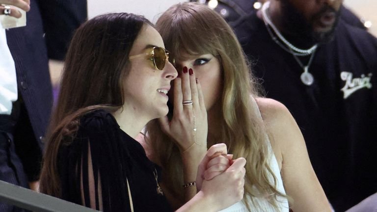 Taylor Swift speaks to musician and actress, Alana Haim in the stands. Pic: Reuters