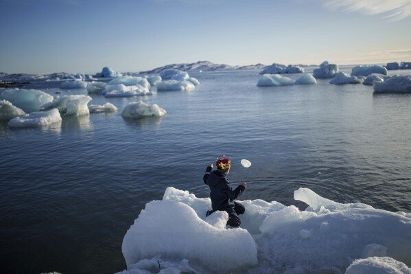 A boy throws ice into the sea in Nuuk, Greenland, Tuesday, March 11, 2025. (AP Photo/Evgeniy Maloletka)