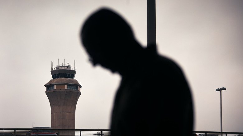 A man stands outside Terminal C with the airport control tower in the background at Newark Liberty International Airport, on May 6, 2025 in Newark, New Jersey.