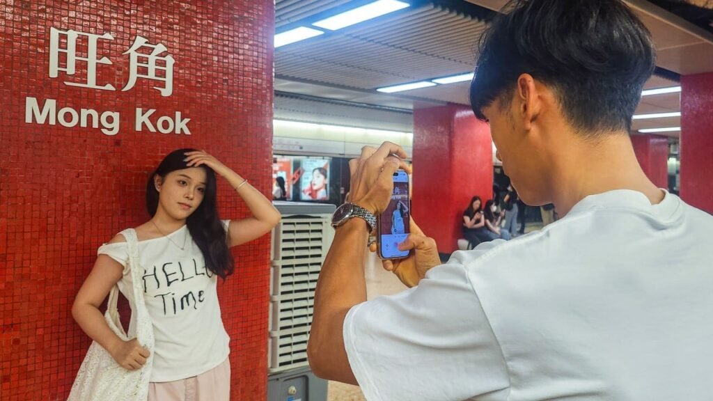 Why are mainland Chinese tourists posing in front of MTR stations in Hong Kong?