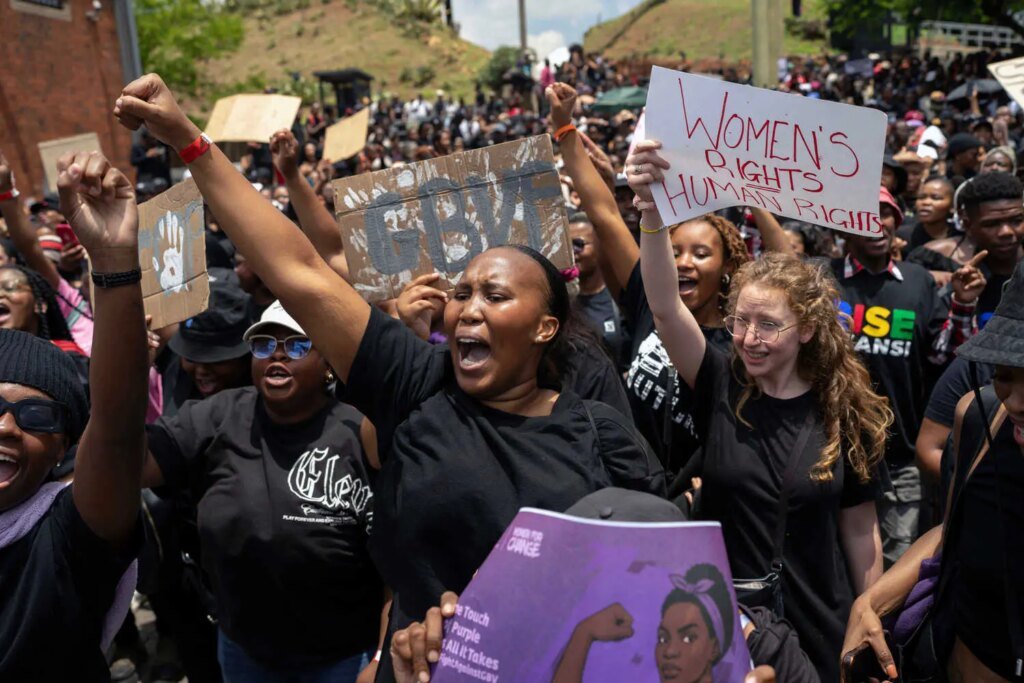 Demonstrators wearing black shirts hold up signs supporting women’s rights.