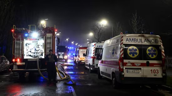 A Ukrainian law enforcement officer stands next to ambulances and a fire truck parked at the site of an air attack in Kyiv on November 25, 202.(AFP)
