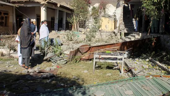 People stand in front of damaged houses that the Afghan Taliban government said were damaged after Pakistan carried out raids(REUTERS)