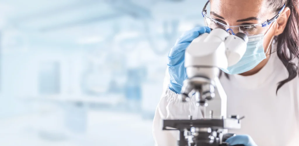 Person in a lab gazing into a microscope.