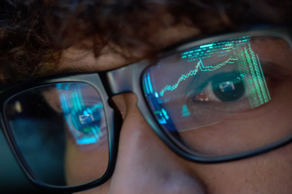 A stock chart displayed on a computer monitor that's being reflected on the eyeglasses of a money manager.