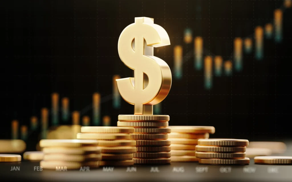 A gold dollar sign on top of stacked gold coins in front of an upward-moving bar chart.