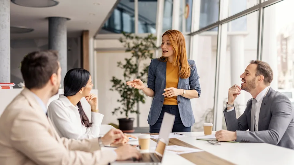 Female manager standing at meeting room and having briefing with her team.