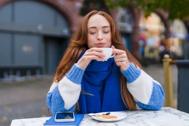 Woman enjoys coffee and a cookie outside in a city setting during the daytime