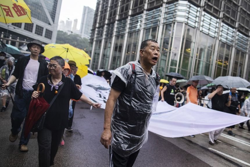 Jimmy Lai holds a banner as he marches along Queen's Road Central during a protest in the Central district of Hong Kong on August 18, 2019.