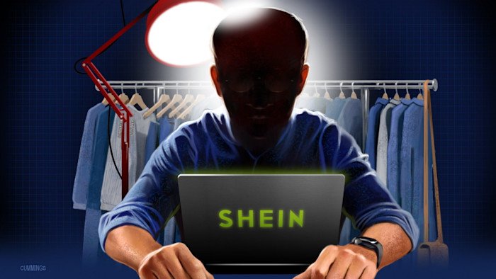 Illustration of Person in the News Xu Yangitan sitting in front of a rack of clothing with his laptop in front of him. His face is dark as a lamp behind his back is illuminating the screen of his laptop.