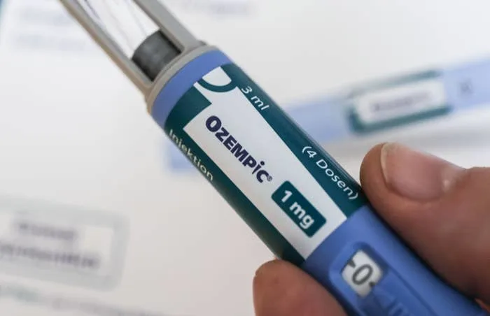 A hand holds an Ozempic injection pen, labeled with "1 mg" and "3 ml" dosage information, used for diabetes management