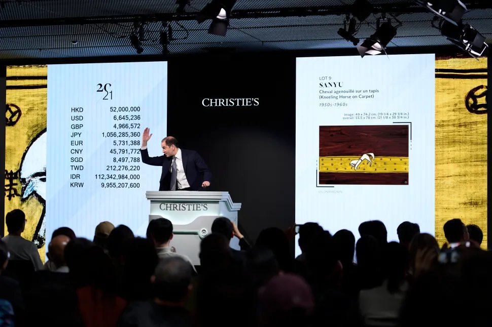 Christie's, Lot 9: Sanyu's Cheval agenouillé sur un tapis (Kneeling Horse on Carpet), 1950s–1960s, hammering at HK$52,000,000. The auctioneer's raised hand signals the final bid.Suggested caption: "Sanyu's Cheval agenouillé sur un tapis hammers at HK$52 million at Christie's Hong Kong, March 27, 2026.