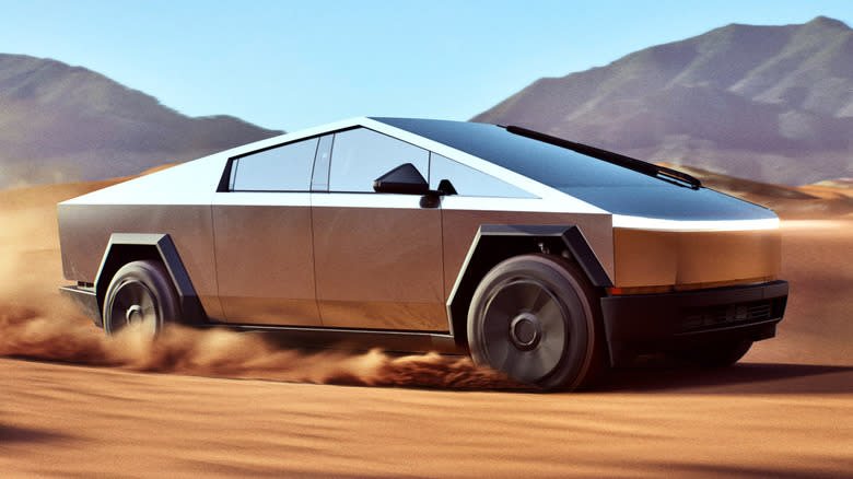 A silver Tesla Cybertruck driving through the desert.