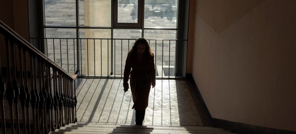 A 16-year-old Ukrainian student, Veronika, walks up a staircase inside Zlatopil Lyceum in Kharkiv region, eastern Ukraine, illuminated by daylight. She continues her education despite ongoing hostilities during the fourth year of the full-scale war.