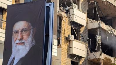 A banner of Iran�s supreme leader Ayatollah Ali?Khamenei is seen next to a building damaged by an Israeli strike in the southern suburbs of Beirut on March?3,?2026. The war launched by the United States and Israel against Iran spread across the Middle East, threatening to plunge the global economy into chaos, with Lebanon and Gulf energy exporters dragged into the conflict. (Photo by AFP) (AFP)