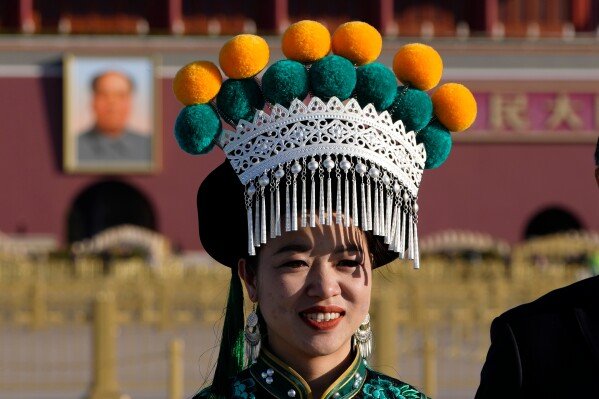 A ethnic minority delegate stand near Mao Zedong's portrait on Tiananmen Square before a plenary session of the National People's Congress (NPC) held at the Great Hall of the People in Beijing, Monday, March 9, 2026. (AP Photo/Ng Han Guan)