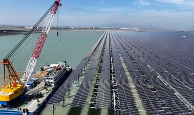 Workers install solar panels with a crane at the CNNC Tianwan tidal flat photovoltaic power plant in Lianyungang (AFP)