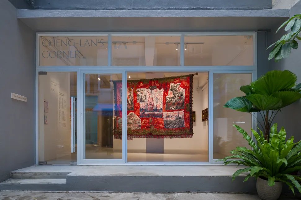 Exterior view of Cheng-Lan's Corner, Hong Kong, showing Cian Dayrit's tapestry A Country, A Body visible through the ground-floor gallery's glass facade.