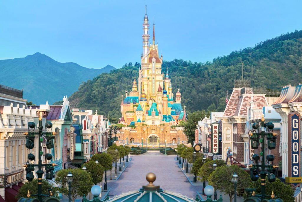 Catch a glimpse of a colorful castle at the end of a bustling street lined with charming shops and lamp posts, with green mountains standing majestically in the background—a scene perfect for your daily recap.