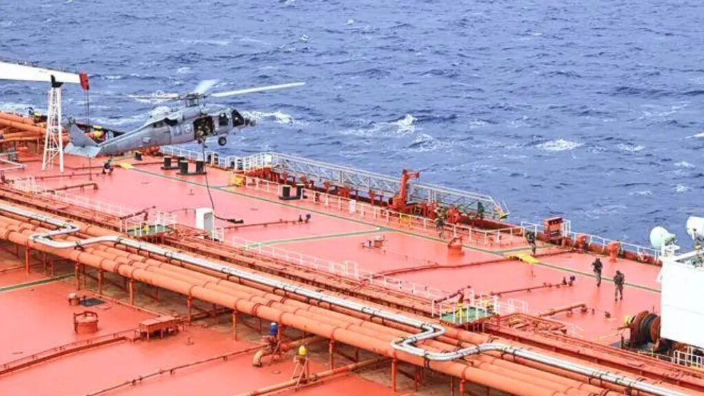 A white U.S. military helicopter hovers over the bright orange sanctioned stateless crude oil tanker M/T Tifani during an U.S. interdiction.