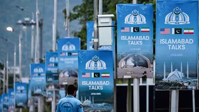 A police personnel walks past posters highlighting Pakistan's mediation of Iran-US peace talks, at the Red Zone area in Islamabad on April 18, 2026. No date has been set for the next round of Iran-US peace talks. (AFP)