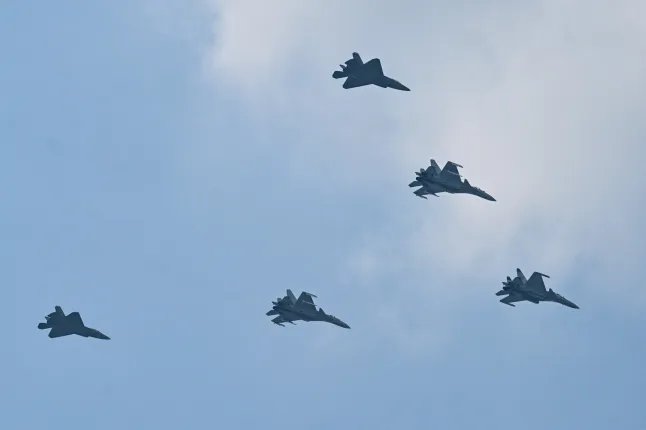Shenyang J-15 (lead and middle aircraft) and Shenyang J-35 (back) jet fighters perform a flyby during a military parade marking the 80th anniversary of victory over Japan and the end of World War II, in Beijing's Tiananmen Square on September 3, 2025.
