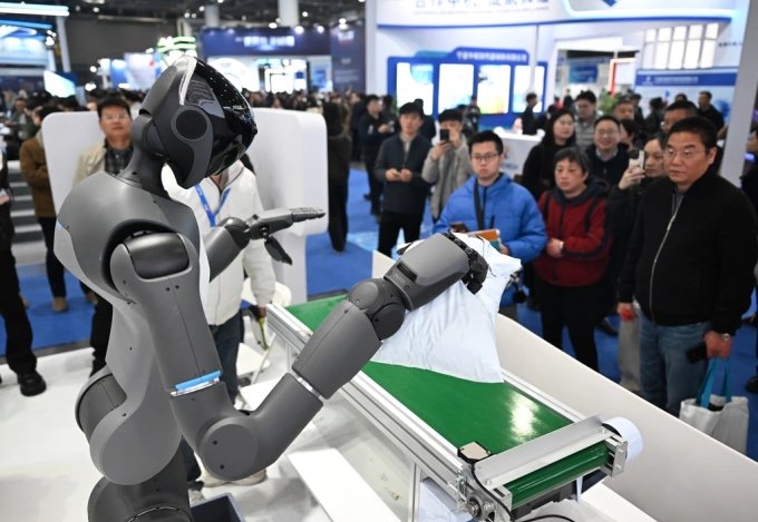 People watch a humanoid robot performs a task at a exhibition in China in March 2026. Photo from X