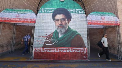 Iranian commuters walks past a large tiled image of Iran's current leader Ayatollah Mojtaba Khamenei, at the entrance to the metro in Tehran. (AFP)