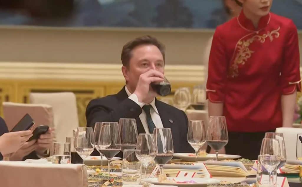 Musk taking a swig of a red drink
